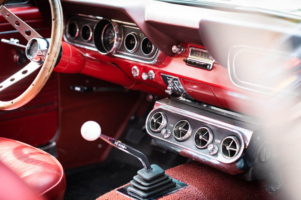 Close-up of a classic car interior with a manual transmission, dashboard gauges, and red upholstery, highlighting vehicle details that may influence repair costs tied to a car insurance deductible.