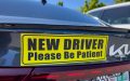 Car with a New Driver Please Be Patient sign on the back, highlighting the purpose of student driver stickers.