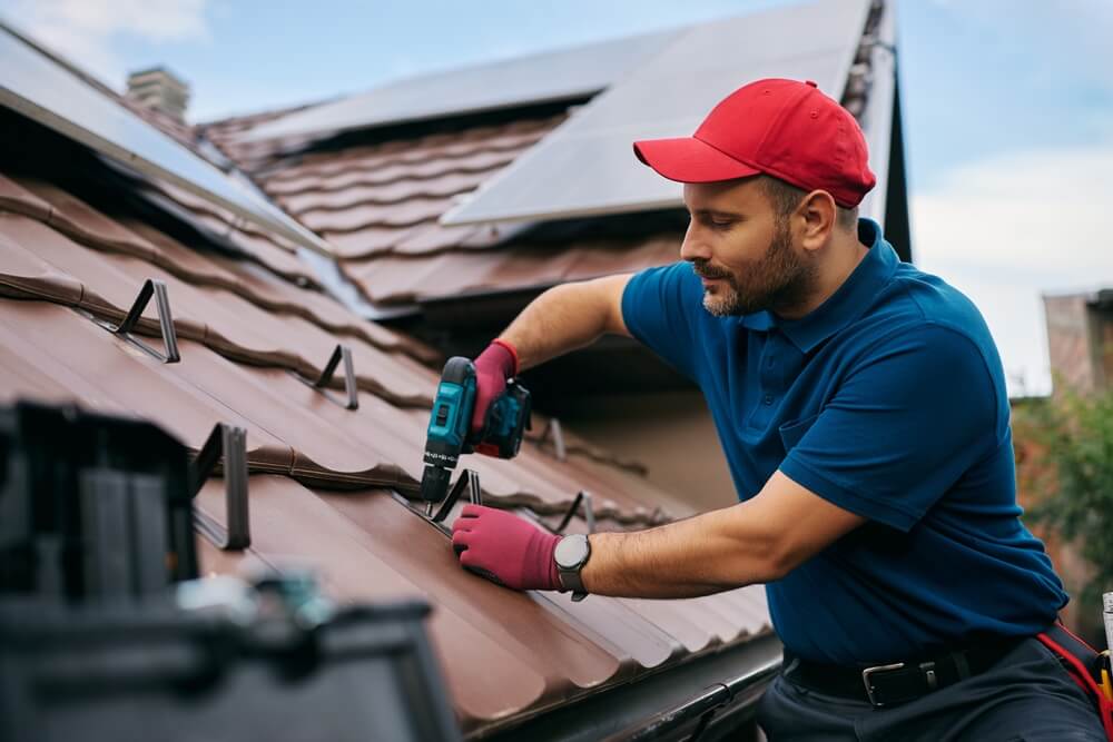 Technician repairing a roof with solar panels after damage, representing repairs covered through home insurance claims.