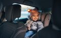 Small child bundled up for winter in a car seat in the back seat of a car.