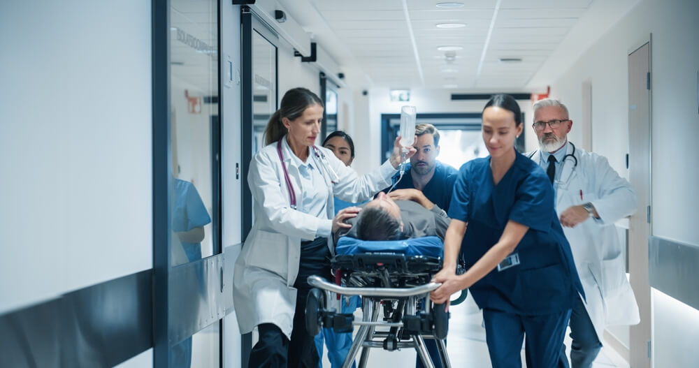 Medical team transporting a patient through a hospital corridor, illustrating emergency and urgent care situations covered by Covered California out of state.