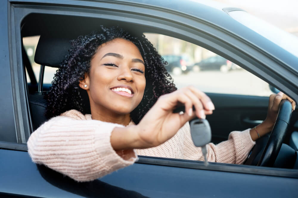 Smiling driver holds car keys through the open window, highlighting Texas Takes Worry Out of Producing Proof of Insurance.