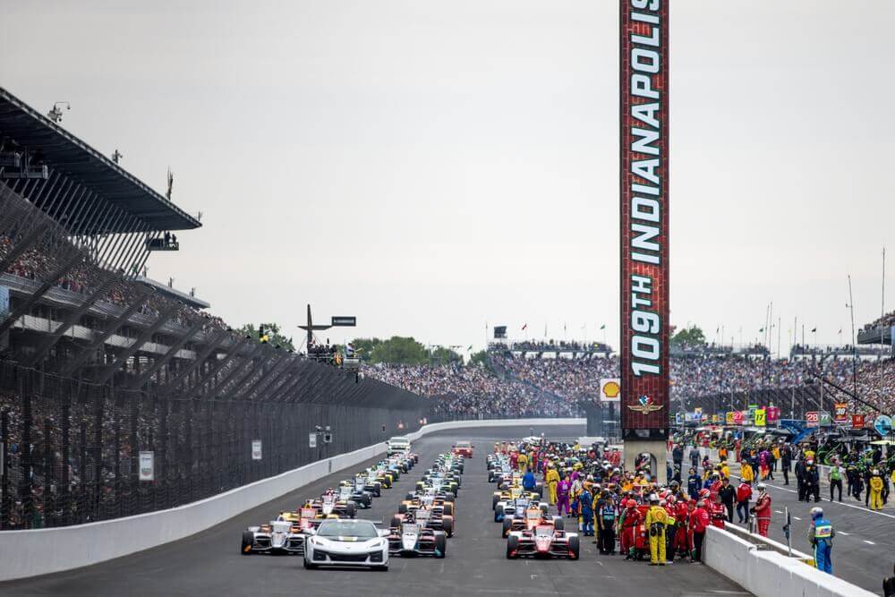 Race cars lined up on the Indianapolis Motor Speedway during a major motorsports event at one of Indianapolis' iconic racing venues.