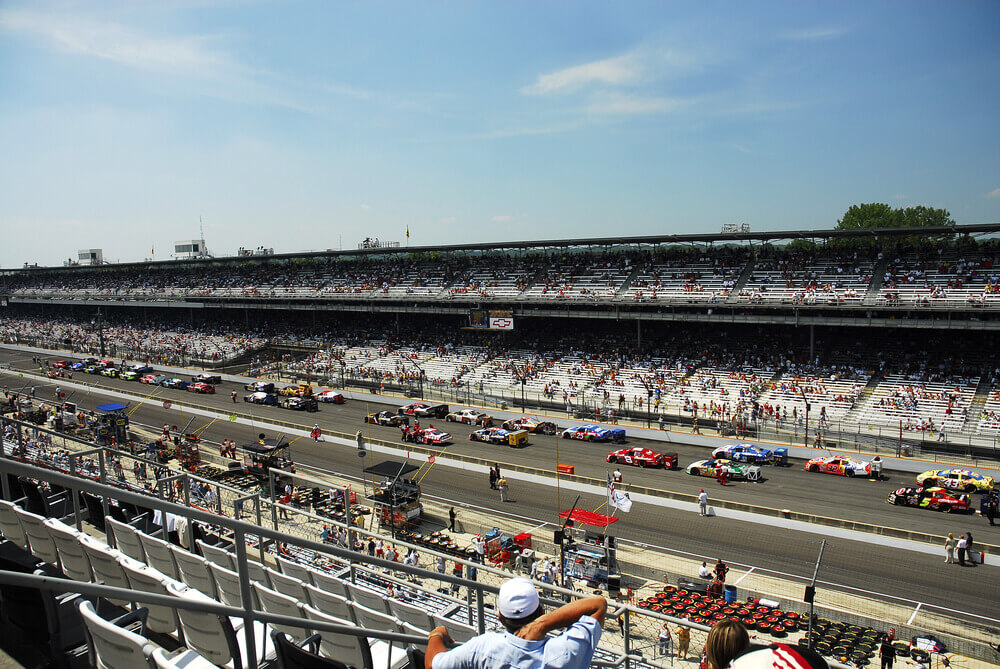 Wide view of the Indianapolis Motor Speedway with race cars on track, showcasing one of the most iconic Indianapolis racing venues.