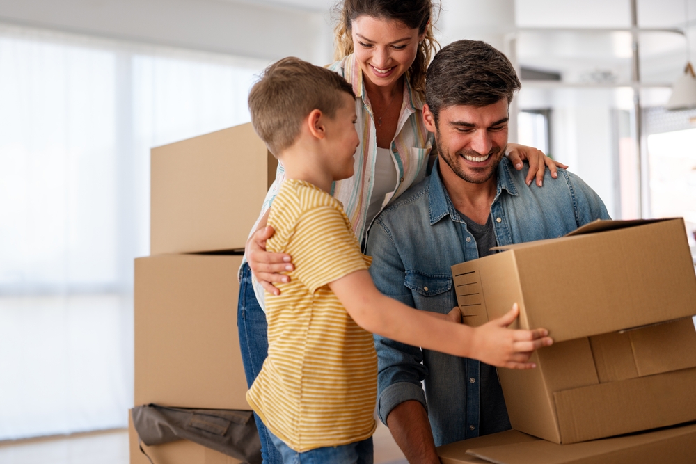 Family insurance gaps concept with parents and child unpacking boxes in a new home