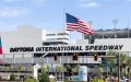 Daytona International Speedway entrance with an American flag flying above the iconic racing venue.