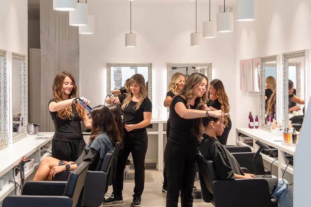 Salon beauty professionals styling clients’ hair in a busy beauty salon.
