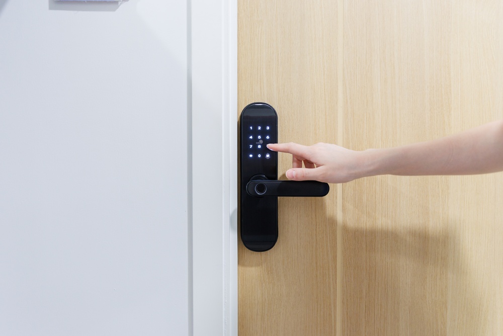 Person entering a code on a smart keypad door lock installed on a front door, illustrating smart home security, keyless entry, and home insurance protection.
