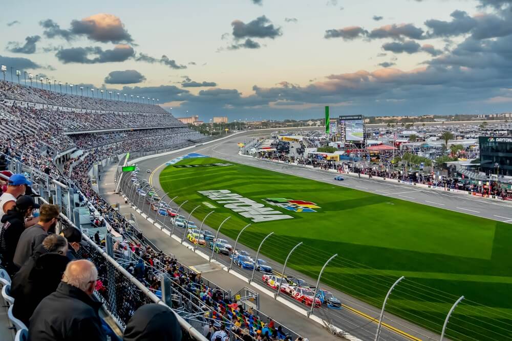 Race cars compete at Daytona International Speedway as spectators fill the grandstands.