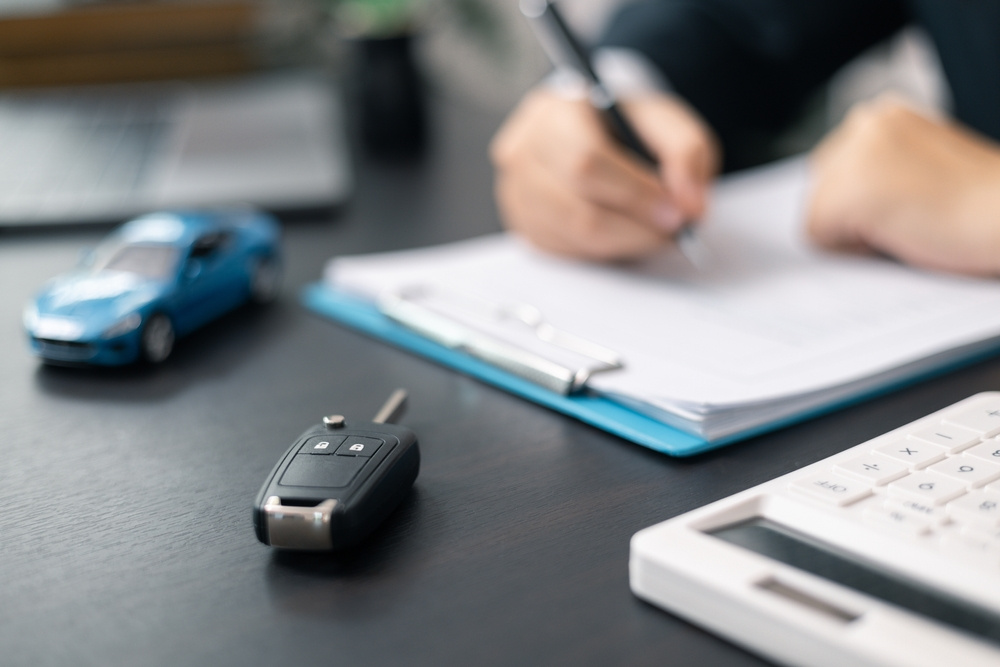 Car keys, paperwork, and a model car on a desk during the car insurance binder process.