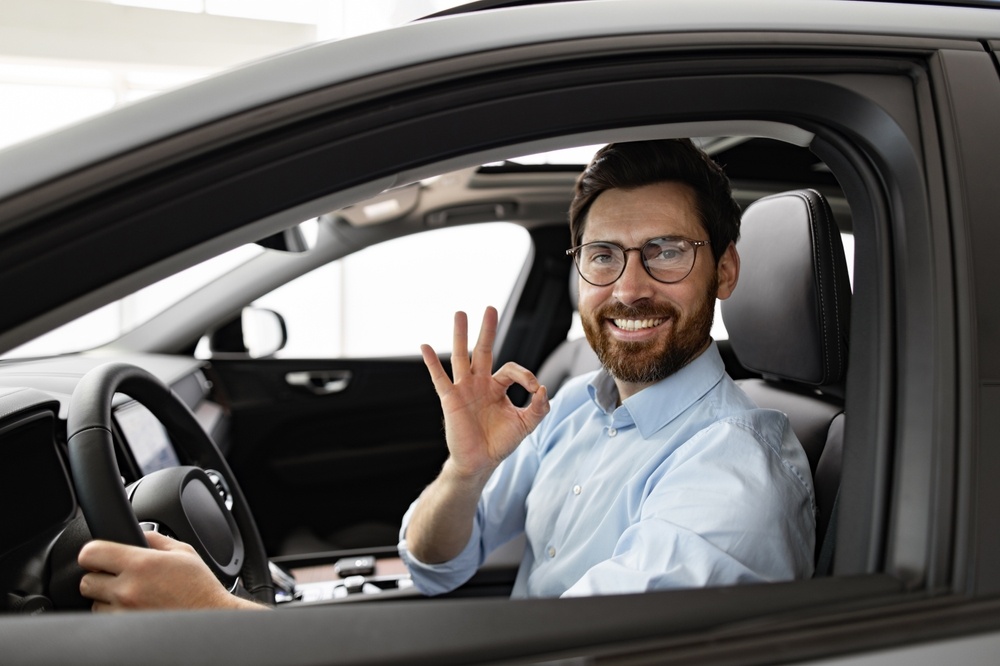 Driver smiling in his car while comparing high-risk auto insurance quotes for suitable coverage options