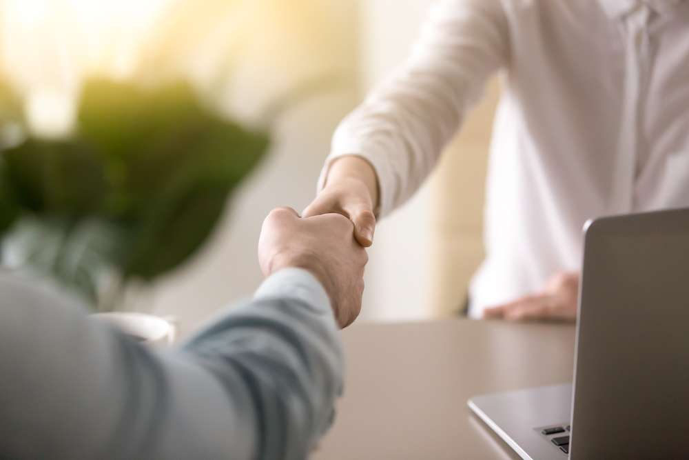 Insurance agent shaking hands with a customer at an insurance agency office.