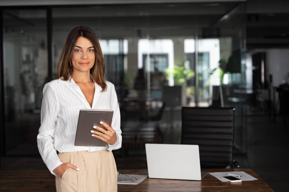 Independent agent holding a tablet in a modern office, helping drivers shop for high-risk auto coverage through an independent agent.