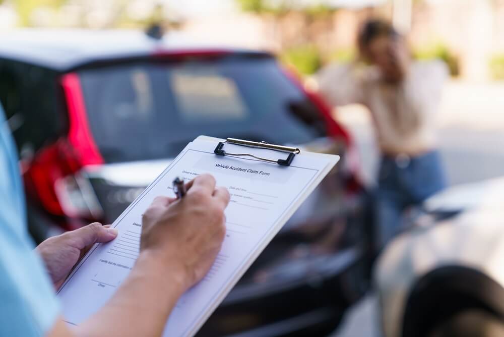 Agent filling out a vehicle accident claim form after a crash, showing why drivers may need to shop for high-risk auto coverage through an independent agent.