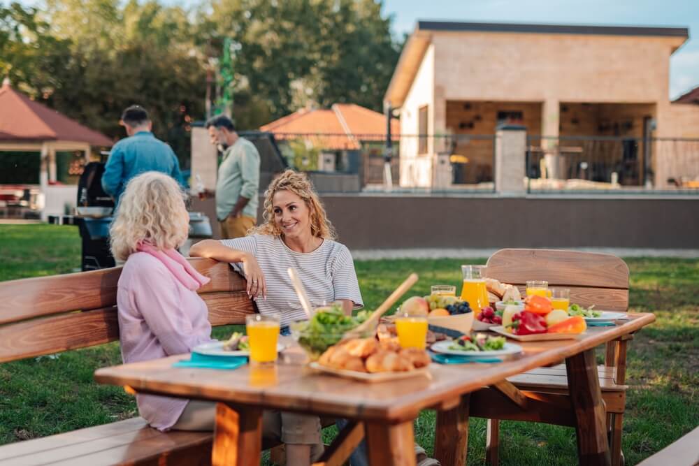 Family and friends enjoy a backyard meal near an outdoor kitchen and patio area, showing how homeowners coverage protects your backyard investments.