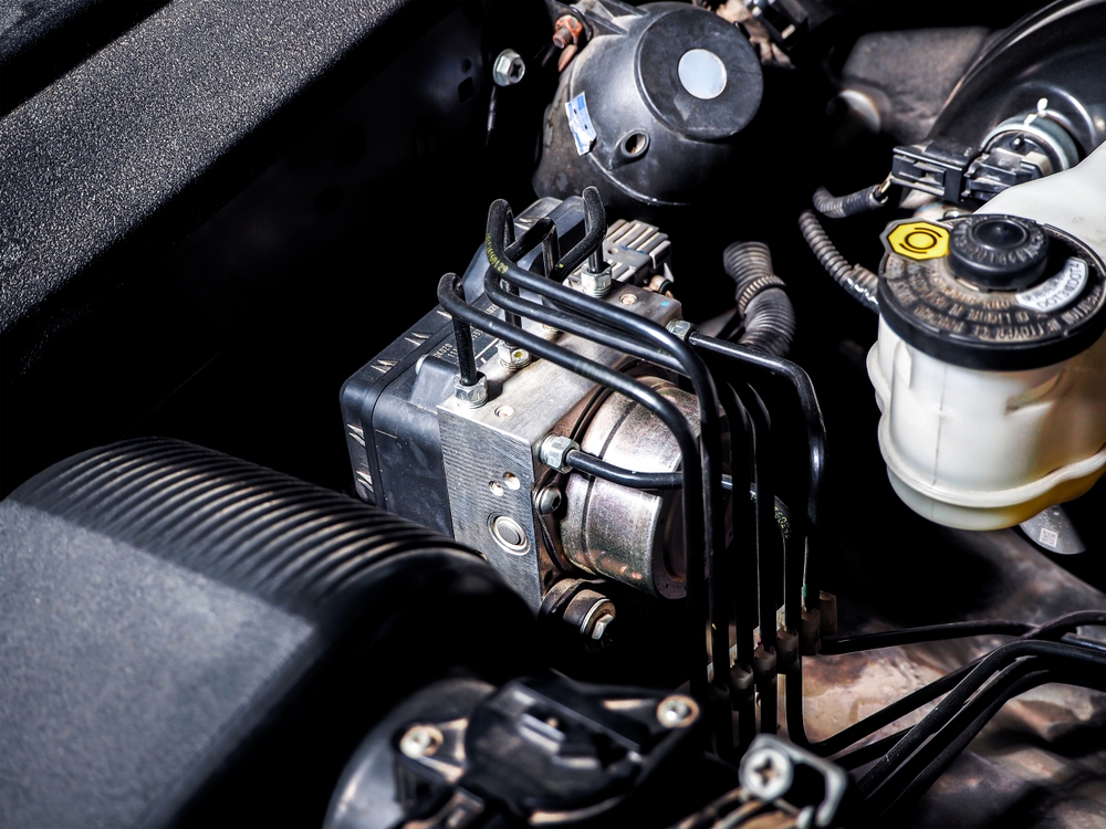Anti-lock braking system (ABS) components and brake lines under a car hood.