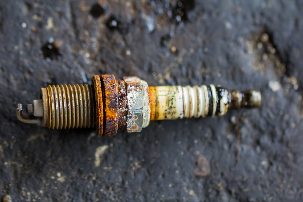 Close-up of a corroded, worn spark plug showing signs of damage and buildup.