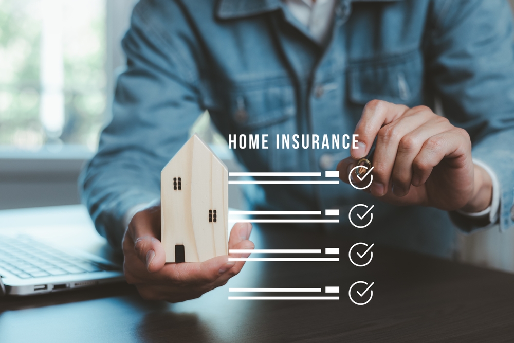 Home insurance checklist displayed beside a model house held by an insurance professional