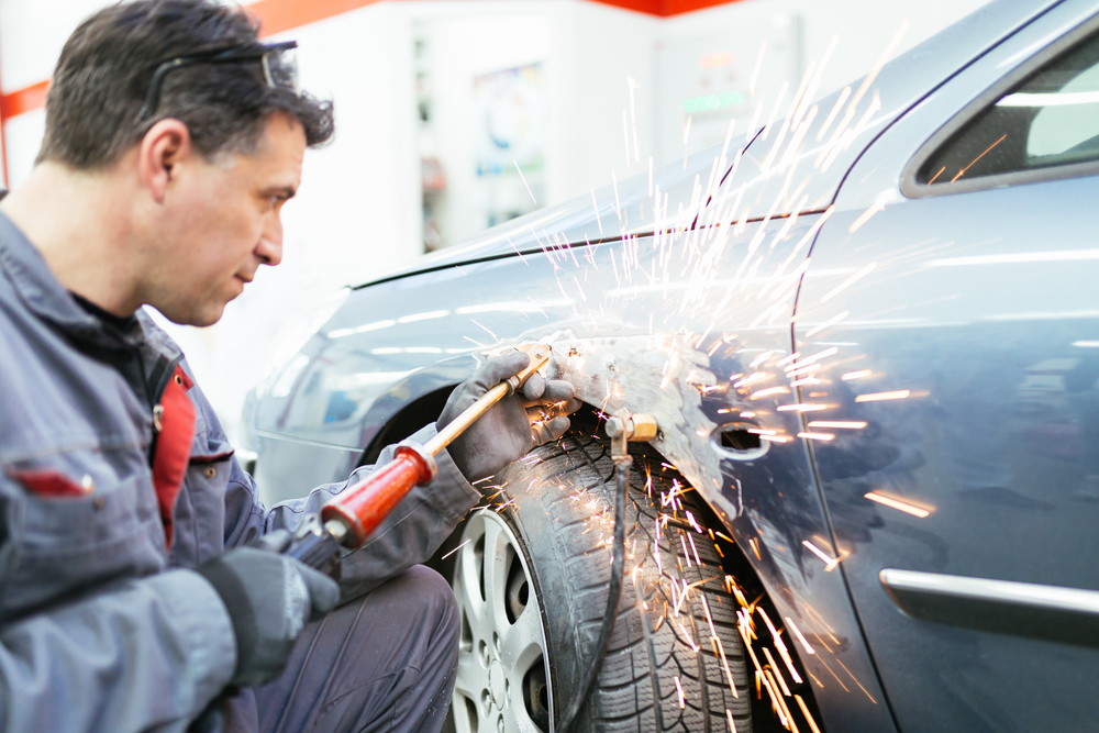 Auto body technician repairs vehicle damage related to diminished value claims after a collision.