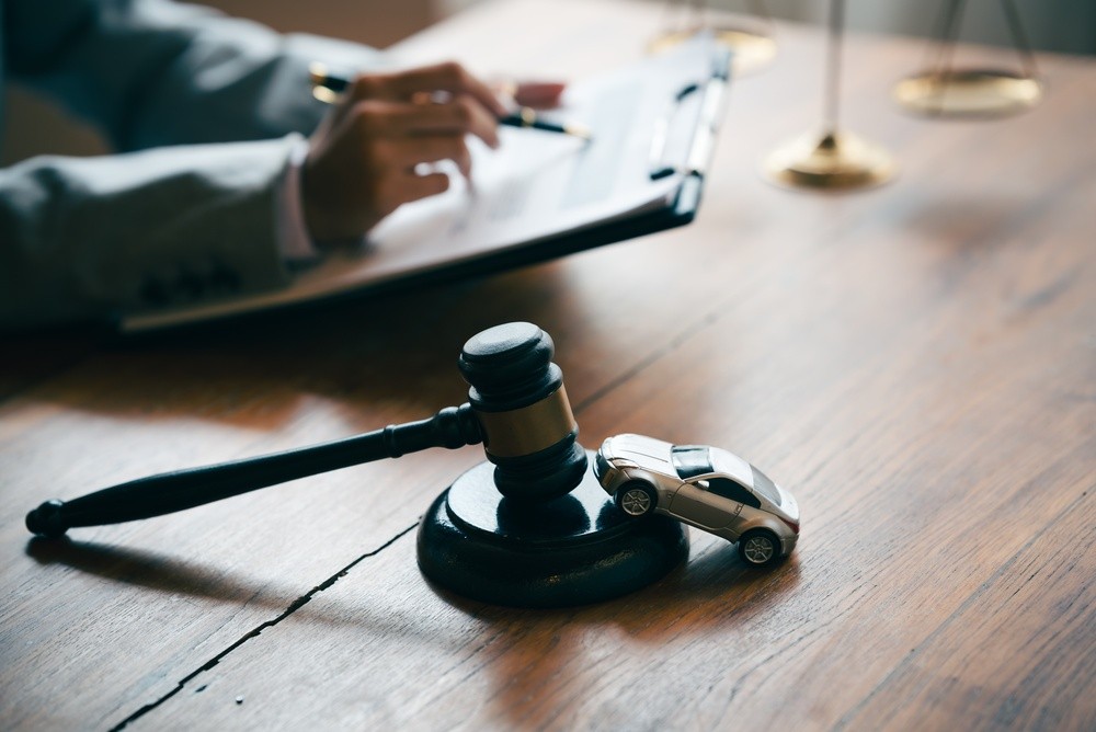 Judge's gavel beside a miniature car, representing legal considerations in no-fault and at-fault auto insurance claims.