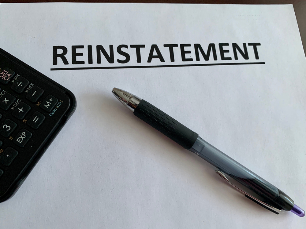 Reinstatement document with a pen and calculator, representing the process of reinstating a canceled car insurance policy.