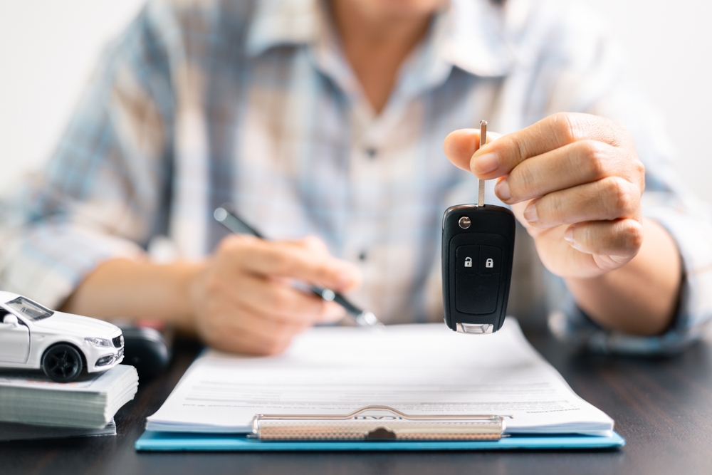 Person holding car keys while completing paperwork for specialty insurance coverage.