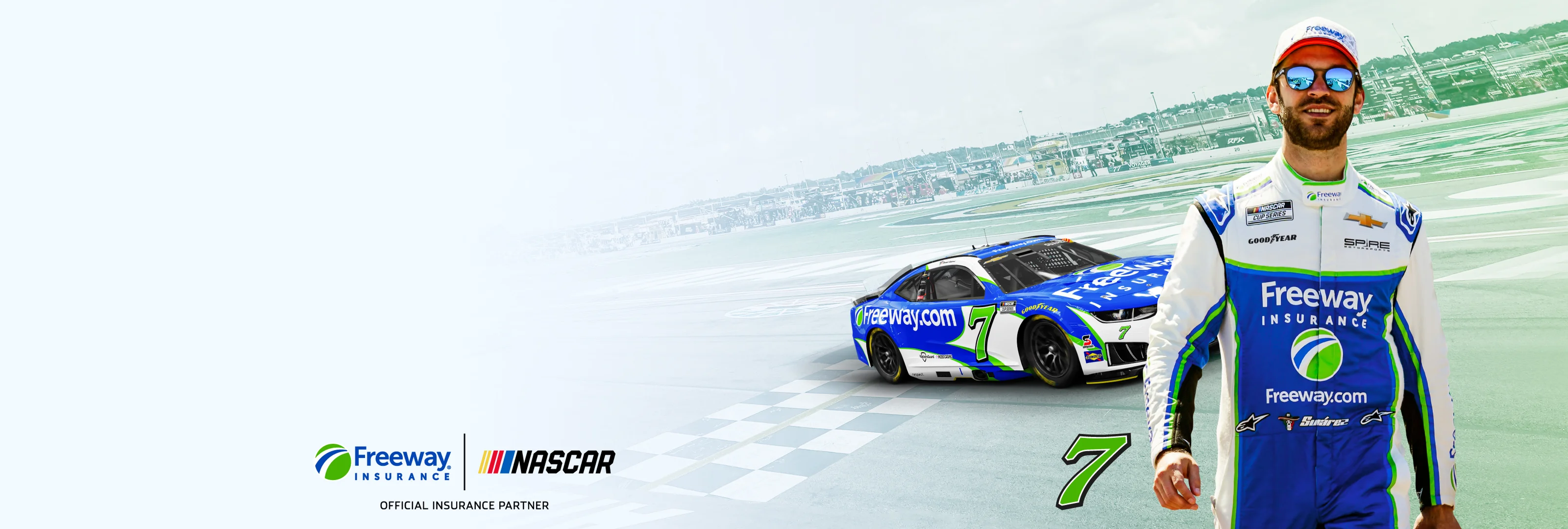 NASCAR driver in Freeway Insurance suit standing next to the number 7 race car on a racetrack.