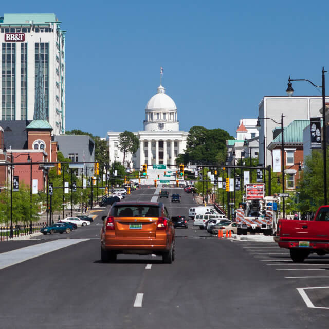 Photo of a road and cars driving toward the Alabama State Capitol in downtown Montgomery, Alabama.