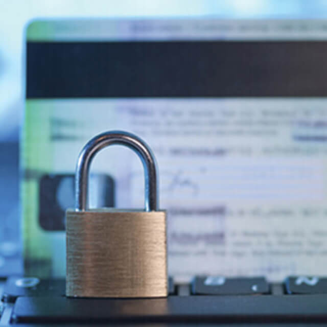 A lock standing on a keyboard in front of a credit card.