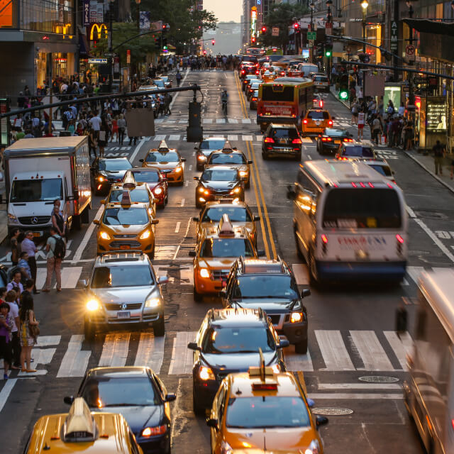 Photo of traffic on a street in New York City with cars, taxis and buses going in both directions.