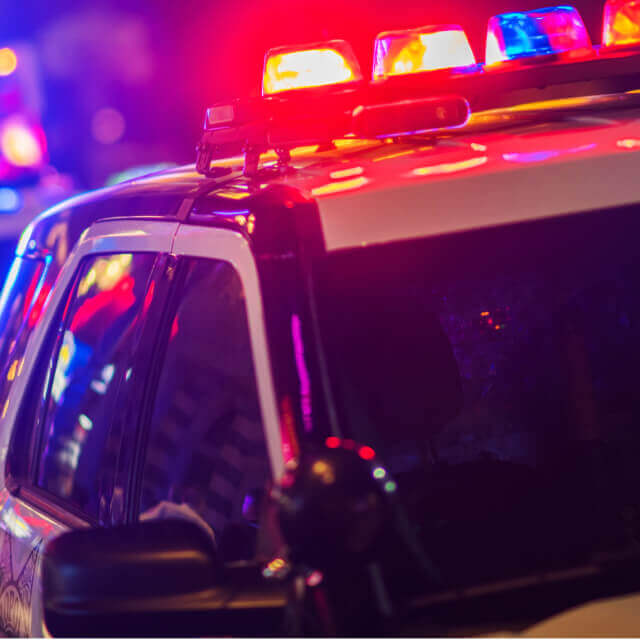 Close up to the co-pilot seat and the top lights of a police car driving with other police cars at night,