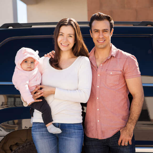 Happy young parents. The mother holds a baby who is wearing a sweater with cute bear ears hoodie.