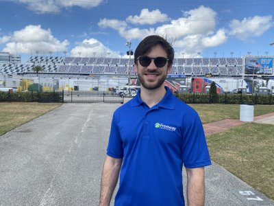 NASCAR Driver Daniel Suarez wearing Freeway Insurance shirt standing outside of race track stadium