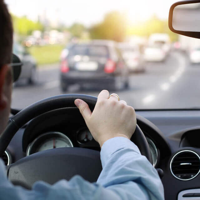 Traffic jam in a Los Angeles city road as seen from the driver's perspective showing his hand on the steering wheel.