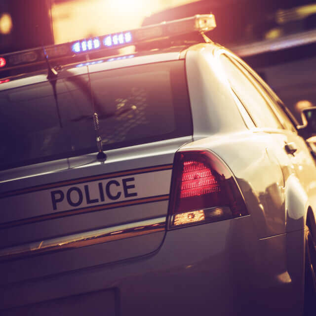 Picture of a parked police car from behind during sunset