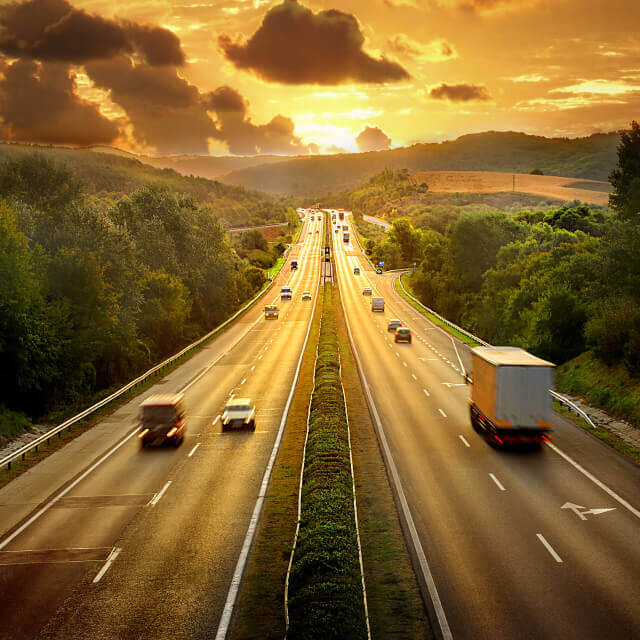 Picture of a Texas busy road during sunset with trees on its borders.