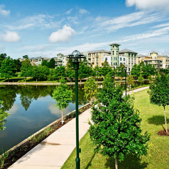 Picture of The Woodlands, TX, luxury master planned community with lake surrounded by big houses, green areas and trees.