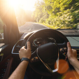 Front view of a man driving a car during sunset