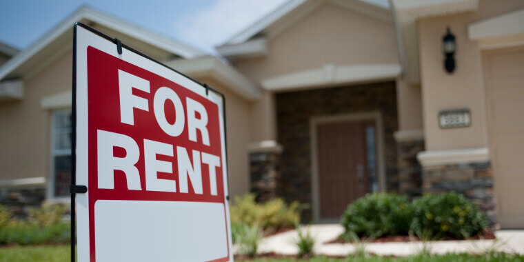 Close up of a sign that says for rent with a house on the background