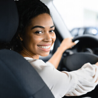 African american woman smiling and looking at the camera sitting in a cars drivers seat