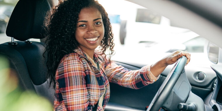 Happy insured young woman driving and smiling
