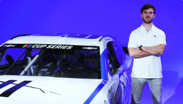 NASCAR Cup Series Driver and Xfinity Series Champion Daniel Suarez stading next to his racing car