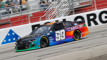 Action shot of Daniel Suarez's race car with the number 99 on the door racing through a nascar track