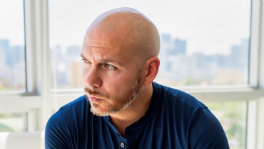 Close up of trackhouse racing co-owner and singer Pitbull looking to his side in front of window