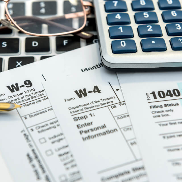 Form W-9 W-4 and 1040 on top of calculators