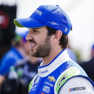 Portrait of NASCAR Cup Series Driver and Xfinity Series Champion Daniel Suarez smiling with a Freeway Insurance branded polo shirt