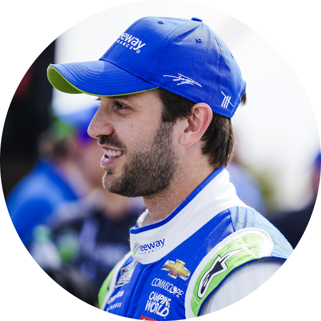 Portrait of NASCAR Cup Series Driver and Xfinity Series Champion Daniel Suarez smiling with a Freeway Insurance branded polo shirt