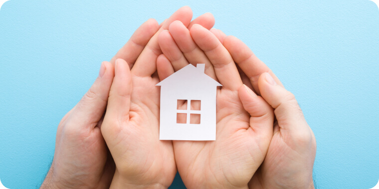 Hands of couple with paper house