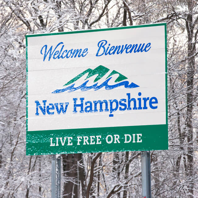 Welcome sign for New Hampshire is covered with fresh fallen snow.