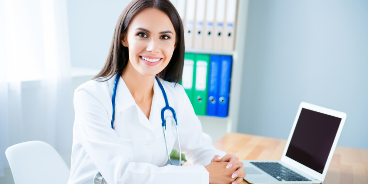 Happy doctor in her office with a laptop